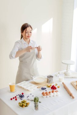 Tatlı pişirirken akıllı telefonunu kullanan hoş bir kız.