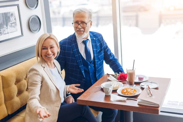 Зріла щаслива пара святкує подію і дивиться на камеру в кафе — стокове фото