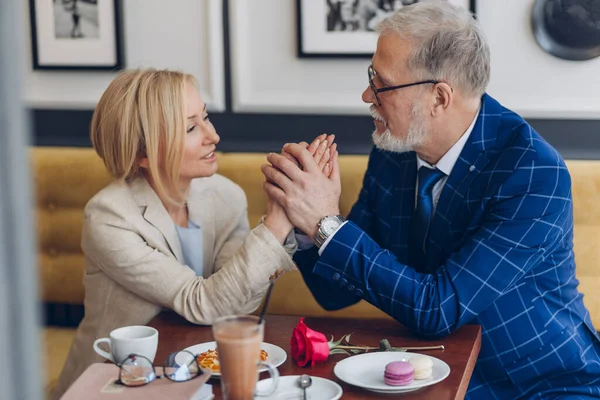 Gelukkig oud geweldig paar op een date hand in hand en genieten van tijd in cafe — Stockfoto