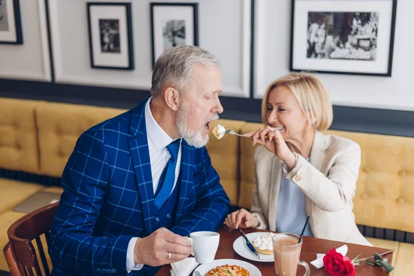 Skrattande vacker gammal dam njuter av morgonmål med sin man — Stockfoto