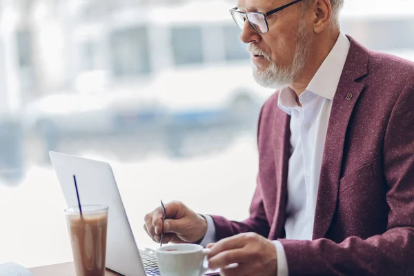 Bonito inteligente velho homem trabalhando com um laptop no café — Fotografia de Stock