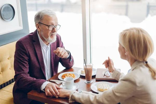 Весела зріла пара снідає в кафе під час спілкування — стокове фото