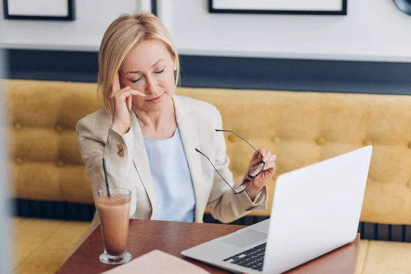 Mujer cansada limpiándose los ojos después de trabajar en el portátil — Foto de Stock