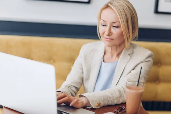 beautiful woman dressed in whilte suit typing something on the laptop