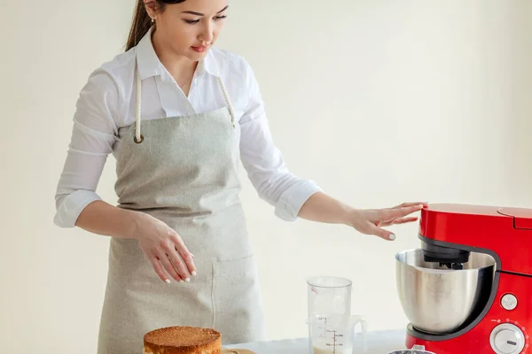 Pretty girl working with a blender to make cream for cake — Stock Photo, Image