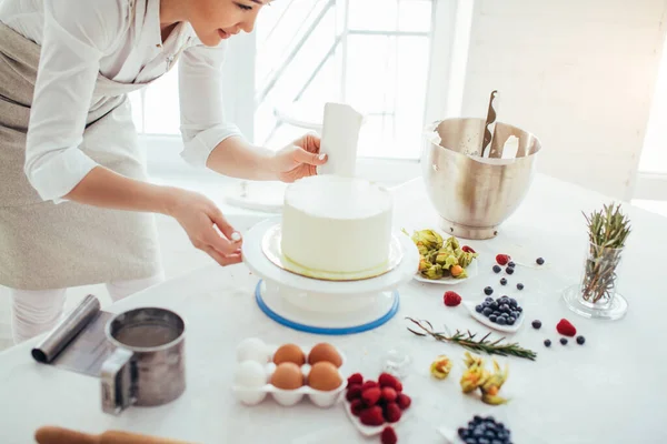 Perfecto suave. chef sosteniendo un raspador de banco verticalmente contra el pastel —  Fotos de Stock