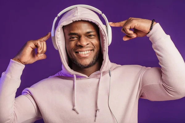 Afrikaanse man in hoodie met hoofdtelefoon geïsoleerd, gelukkige uitdrukking. Muziek, mensen. — Stockfoto