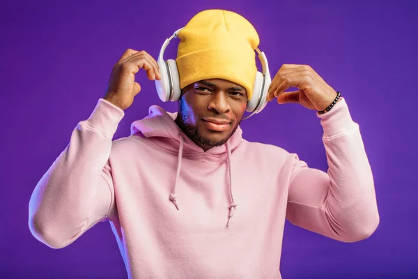 Homme africain en sweat à capuche avec écouteurs isolés, expression heureuse. Musique, gens — Photo