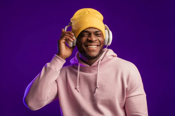 Homme africain en sweat à capuche avec écouteurs isolés, expression heureuse. Musique, gens — Photo