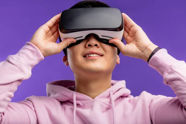 Asiatico giovane uomo utilizzando realtà virtuale auricolare isolato su sfondo viola — Foto Stock