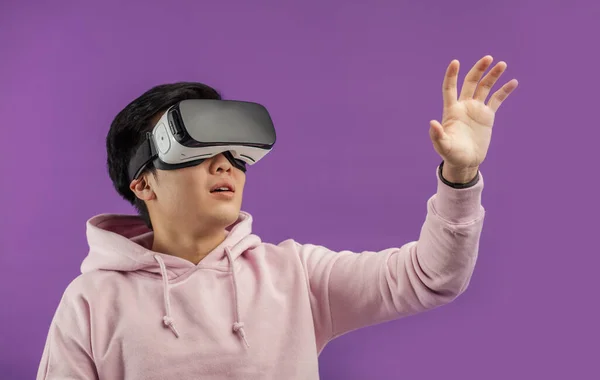 Asiatico giovane uomo utilizzando realtà virtuale auricolare isolato su sfondo viola — Foto Stock