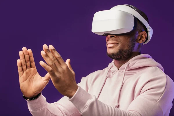 Hombre africano con gafas de realidad virtual aisladas sobre fondo púrpura oscuro —  Fotos de Stock