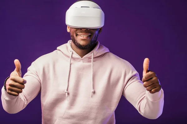 Afrikaanse man draagt virtual reality bril geïsoleerd op donker paarse achtergrond — Stockfoto