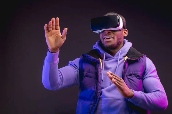 Africano uomo indossare realtà virtuale occhiali isolato su sfondo viola scuro — Foto Stock