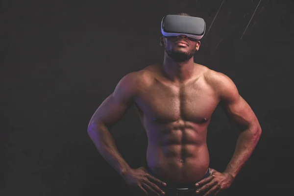Uomo africano con corpo muscolare atletico indossando cuffie realtà virtuale. — Foto Stock