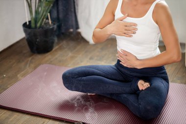 Genç kadın bacak bacak üstüne atarak oturur ve aroma çubuklarıyla rahatlar.