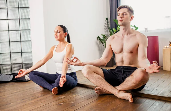 Evli, güzel bir çift meditasyon yapıyor, evde yoga egzersizleri yapıyor. — Stok fotoğraf
