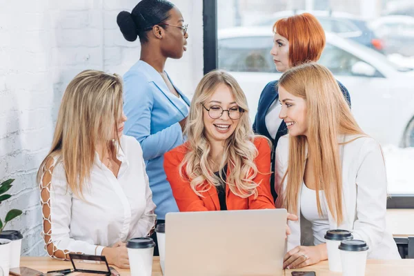 Grupo de mujeres jóvenes discutiendo proyecto durante el proceso de trabajo con el ordenador portátil. — Foto de Stock