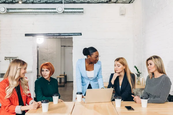 Africano chefe feminino dizendo fora de seus funcionários do sexo feminino, sentado na sala de reuniões . — Fotografia de Stock