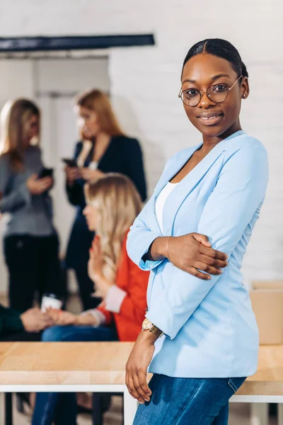 Mulher negra de negócios ajustando suas roupas em um fundo cinza — Fotografia de Stock
