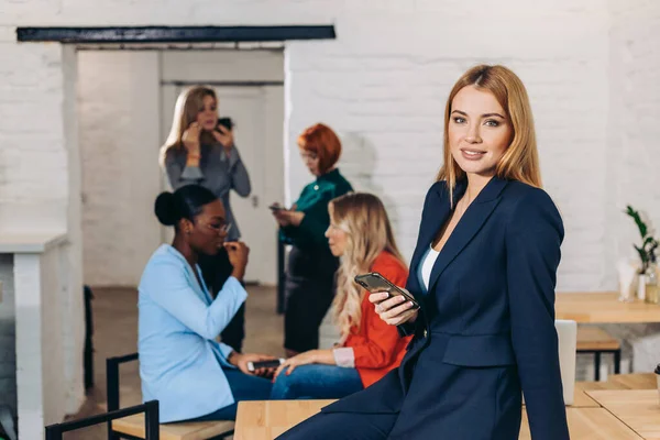 Vrouw die een smartphone in haar hand houdt en gebruikt tegen kantoorachtergrond — Stockfoto