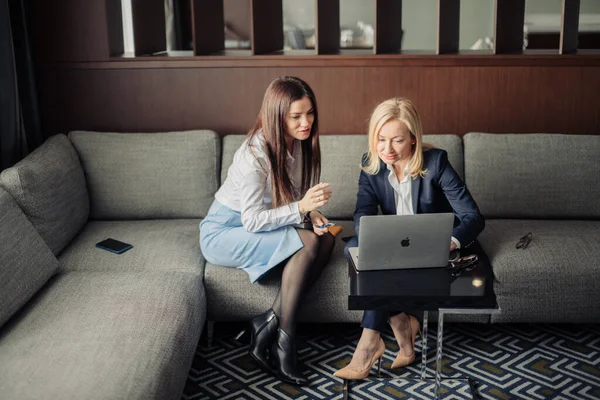 Nahaufnahme zweier seriöser Mitarbeiter, die online mit einem Laptop im Büro zusammenarbeiten — Stockfoto