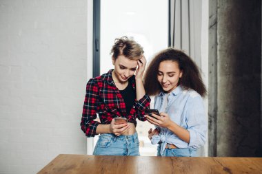 Hoş, mızmız kadınlar ellerinde akıllı telefonlar ve bir şey tartışıyorlar.