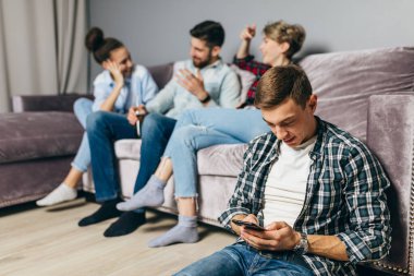 Çek tişörtlü genç hoş adam cep telefonunu kullanıyor.