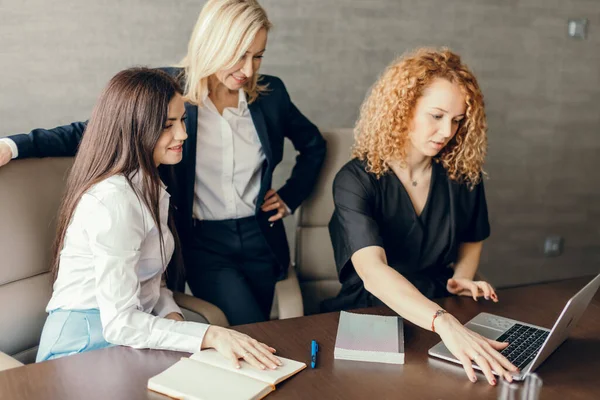 Três estilistas femininas trabalhando em equipe, usando laptop no café. — Fotografia de Stock