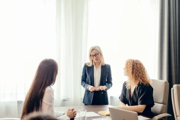 Tres jóvenes empresarias en la reunión en una sala de conferencias — Foto de Stock