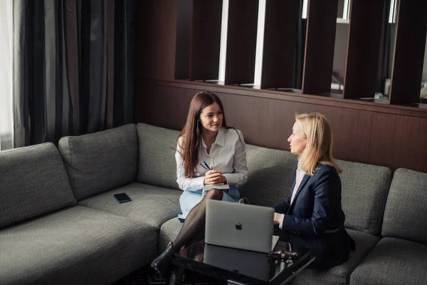 Close up of two serious employees co-working on line with a laptop at office