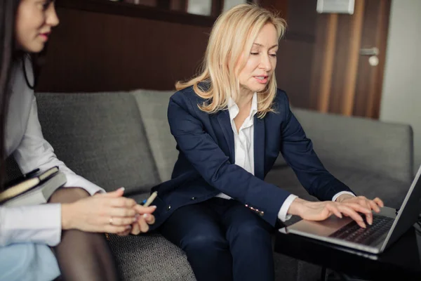 Två unga kvinnor sitter på soffan och tittar på laptop, analysera risker. — Stockfoto