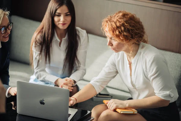 Tres diseñadoras de moda trabajando en equipo, usando un portátil en la cafetería. — Foto de Stock