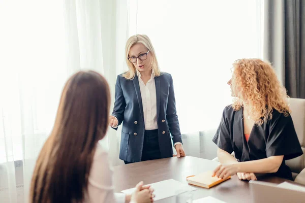 Tres jóvenes empresarias en la reunión en una sala de conferencias — Foto de Stock