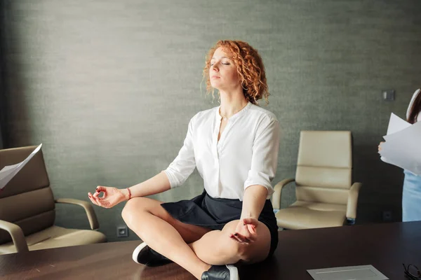 Спокойная деловая женщина медитирует в позе лотоса йоги с летающими бумагами вокруг — стоковое фото