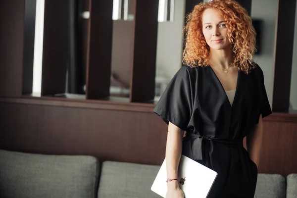 Ung kvinnlig modedesigner i trendiga svarta overaller poserar med laptop. — Stockfoto