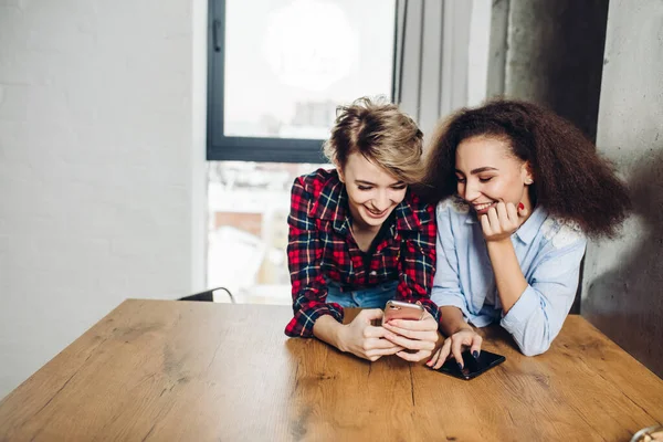 Twee positieve mooie vrouwen die hun smartphone gebruiken — Stockfoto