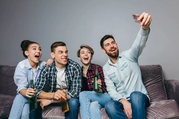 Amigos alegres están sentados en el sofá tomando foto selfie — Foto de Stock