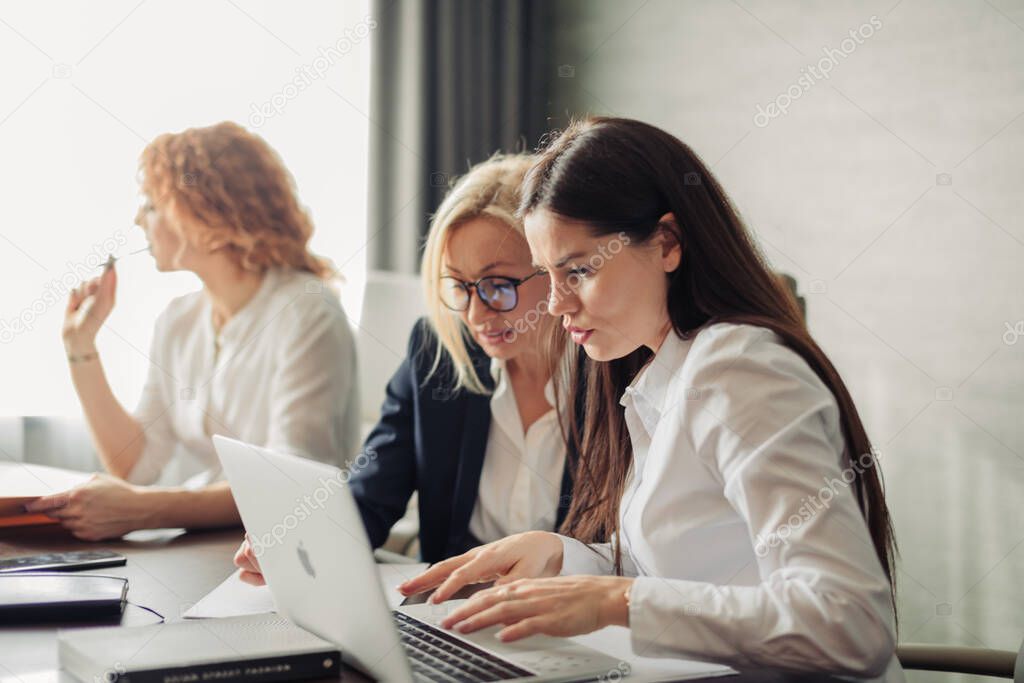 Female team of young caucasian women entrepreneurs working with laptop computer