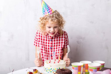 Aç şirin bir çocuk lezzetli pastaya bakıyor.