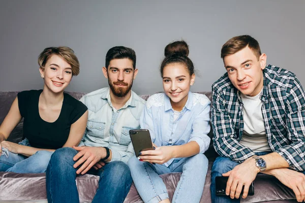 Mujer joven con un peinado está mostrando un nuevo teléfono inteligente a sus mejores amigos — Foto de Stock