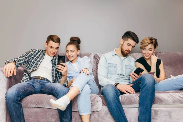 Barátok mobiltelefonok ülnek a kanapén, és figyelmen kívül hagyják egymást — Stock Fotó