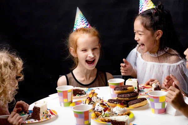 테이블에 앉아서 케이크를 먹는 여자 애들은 웃고 있습니다. — 스톡 사진