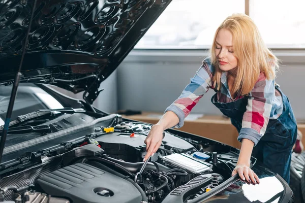 Mujer mecánica seria que trabaja en su propio taller de reparación — Foto de Stock