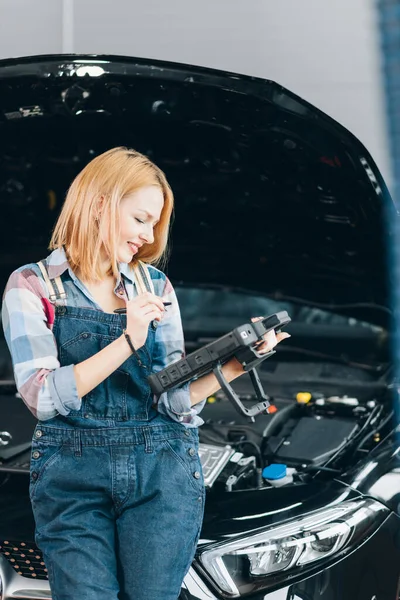 Happy girl controlling the condition of a vehicle — Stock Photo, Image