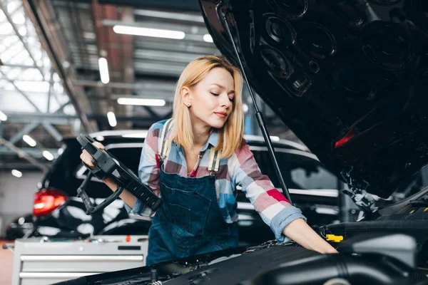 Mujer de pelo justo utilizando tableta digital mientras se diagnostica el motor del coche. — Foto de Stock