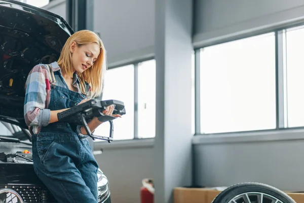 Agradable chica rubia usando un escáner de diagnóstico automotriz — Foto de Stock