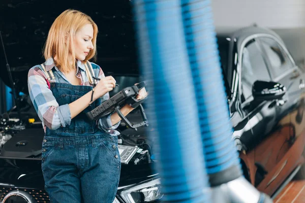 girl with a diagnostic tool which tell you whats wrong with your car