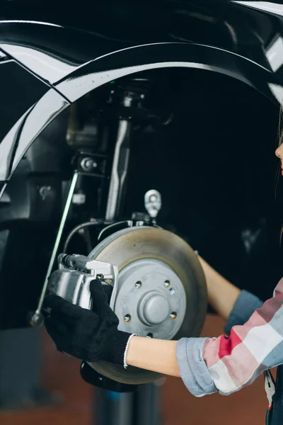 Mãos femininas segurando disco de frenagem. mulher reparar um pneu do carro — Fotografia de Stock