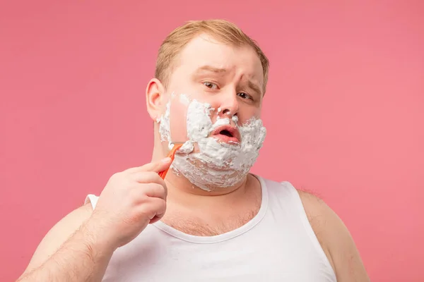 Primo piano di uomo adulto scontento rasatura con schiuma e rasoio isolato su rosa — Foto Stock